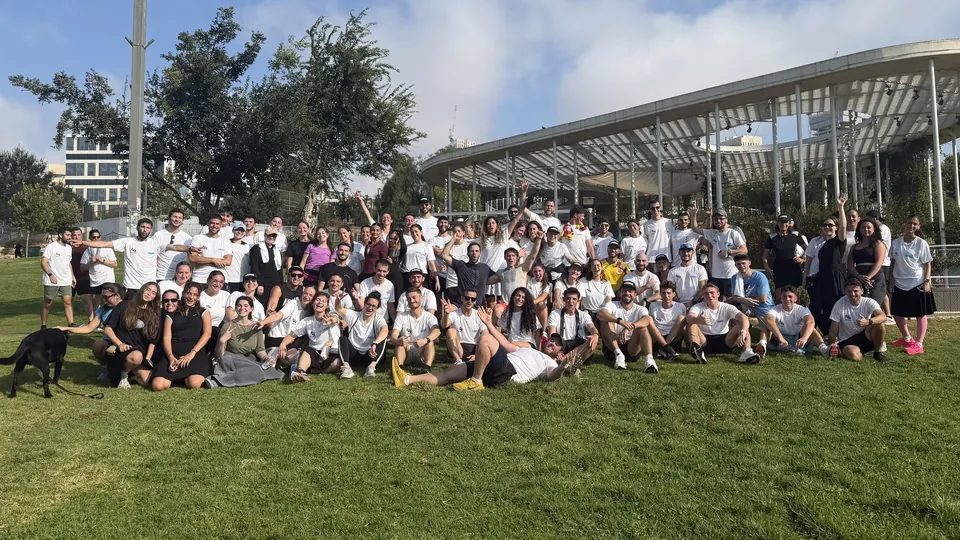 A big crowd of Run Club Jeru runners cheering together on the lawn in Gan Sacher Park.